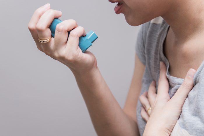 Woman using a pressurized cartridge inhaler