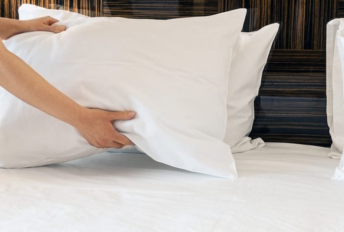 hands placing pillows on the bed