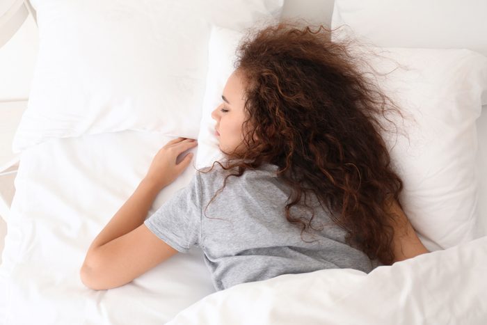 Morning of young African-American woman sleeping in bed