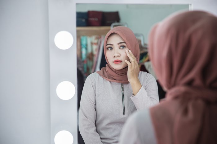 woman wearing makeup looking at herself in the mirror