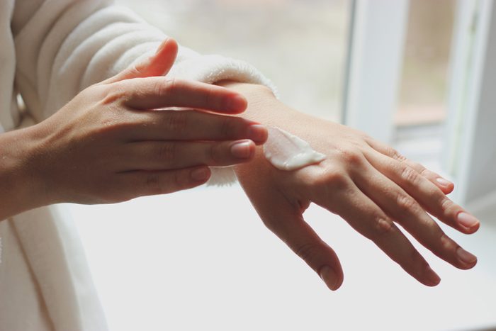woman putting lotion or sunscreen on hand