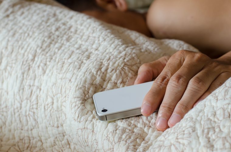 Man sleeping in bed and holding a cell phone 