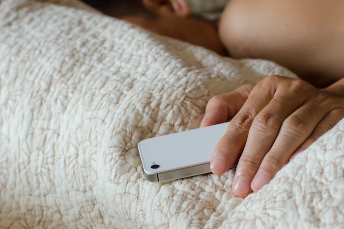 Man sleeping in bed and holding a cell phone 