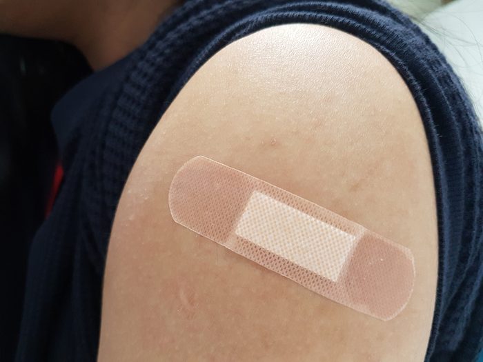 A band-aid is on shoulder of a woman after had influenza vaccine. Health care concept. Prevent influenza. 