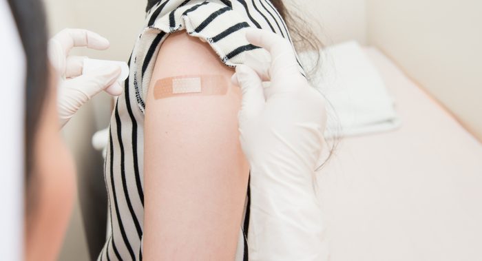 Adhesive bandage on arm after injection vaccine or medicine,ADHESIVE BANDAGES PLASTER - Medical Equipment,Soft focus Adhesive bandage on a female brachium after vaccination,