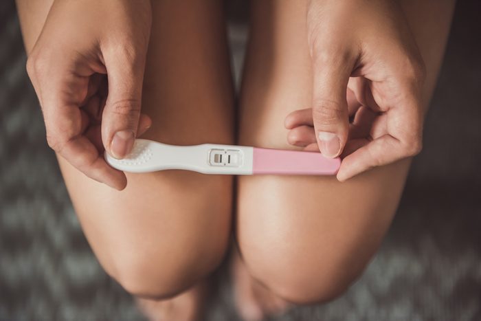 Cropped image of woman holding a pregnancy test on her knees