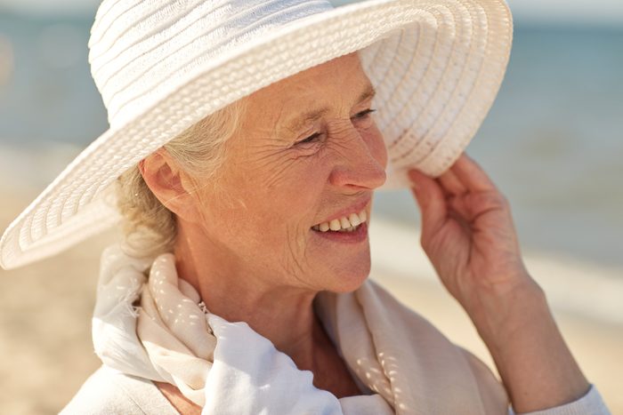 older woman smiling and wearing sun hat