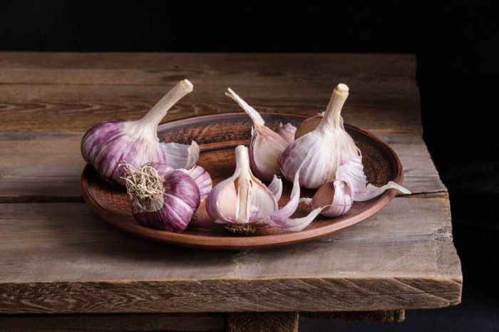  Purple-tinged garlic cloves on a plate on an old wooden table