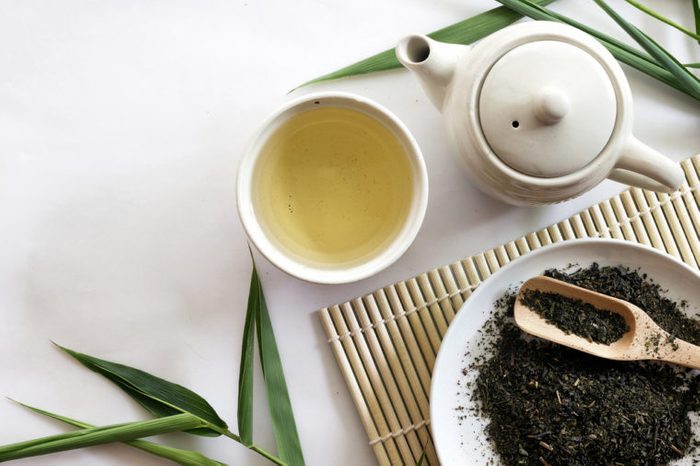 teapot and cup of herbal green tea on bamboo matt