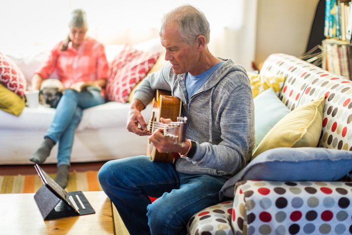 man learning how to play the guitar at home