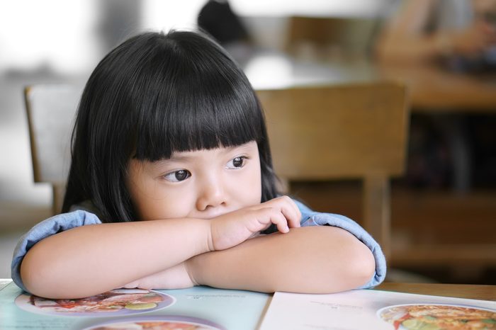 Asian children cute or kid girl lonely and sad with tears in the eye on food table because miss mom and dad or parents do not care with thinking something