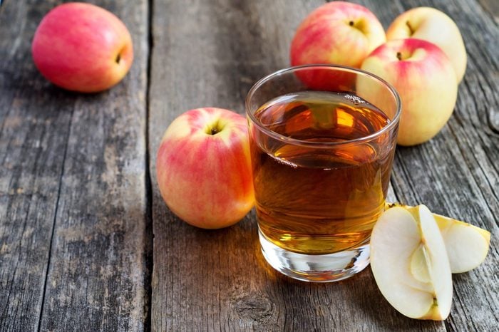 apple juice in a glass and apples on wooden background