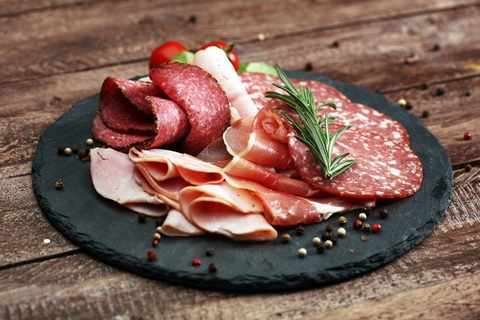 Food tray with delicious salami, pieces of sliced ham, sausage, tomatoes, salad and vegetable - Meat platter with selection - Cutting sausage and cured meat on a celebratory table.