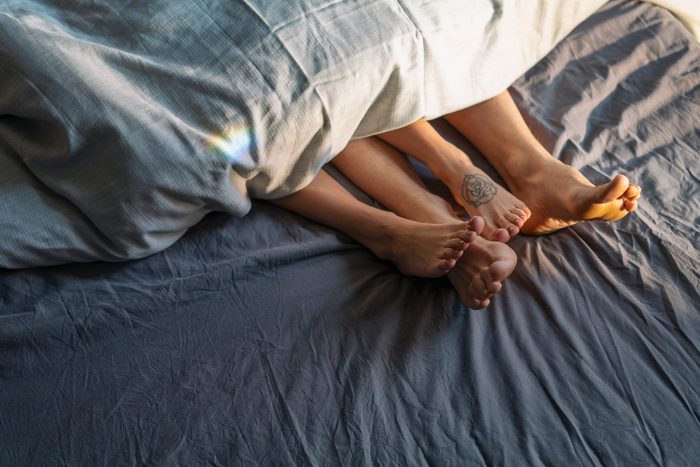 couple's feet sticking out of bed covers
