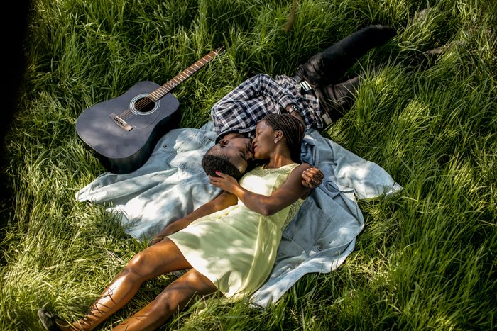 Beautiful fun happy smiling African American couple laying in grass