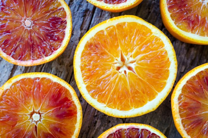 Sliced blood oranges texture. Citrus background. Cut ripe juicy Sicilian Blood oranges fruits on old wooden background. Top view.