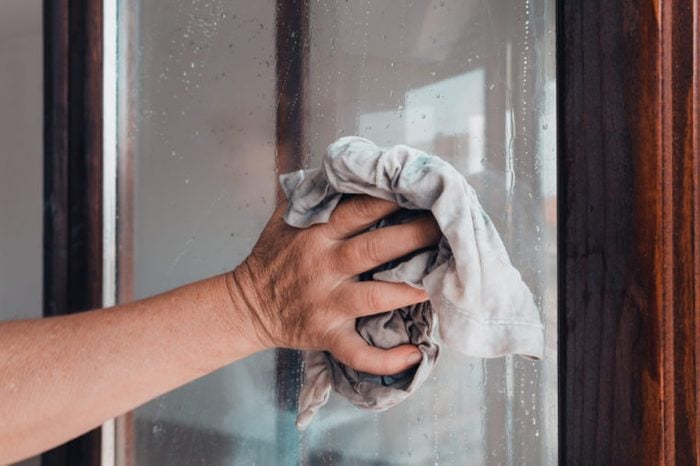 A person's hand holding an old rag while cleaning a window