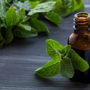 Essential aroma oil with peppermint on wooden background.