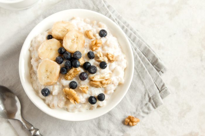 Oatmeal porridge with walnuts, blueberries and banana in bowl - healthy rustic breakfast