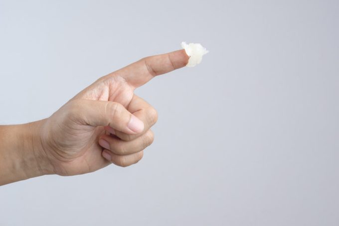 Hand with petroleum jelly on index finger on white background