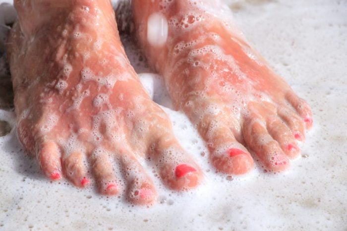 Woman's feet in the shower covered with shower gel foam