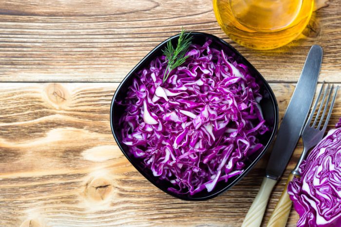 Red cabbage salad on wooden background. Top view.