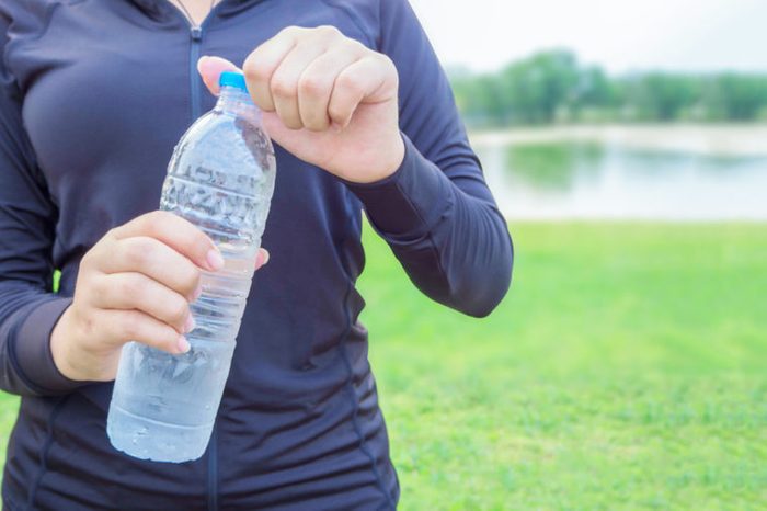 Close-up plastic water bottle in woman hand After Exercise