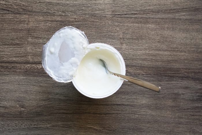 overhead view of plain or natural yoghurt in yogurt pot with dessert spoon