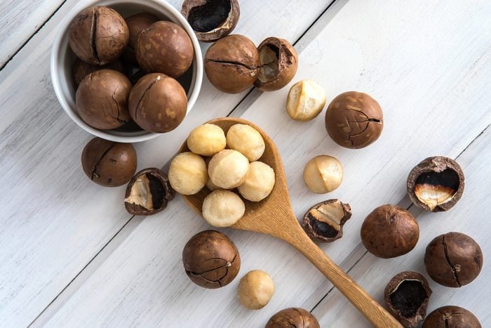 Close up Macadamia nuts on white wooden background , superfood and healthy food concept , overhead or top view shot with vintage color tone