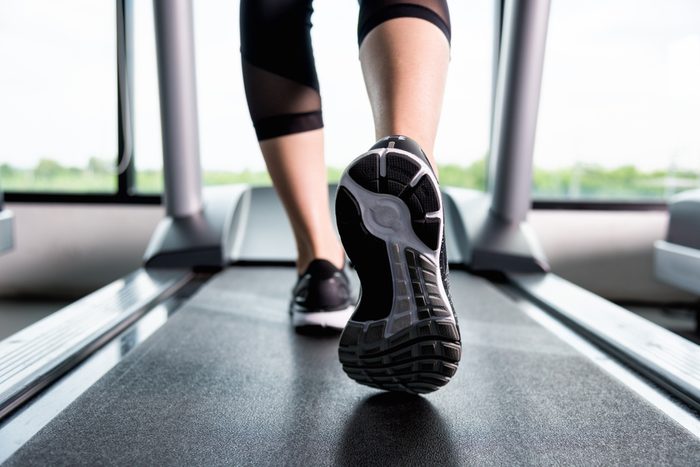 Close up shoes woman's muscular legs feet running on treadmill workout at fitness gym
