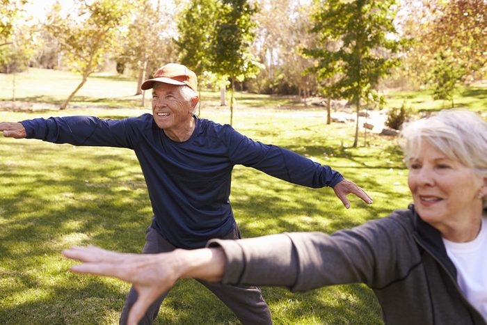 Senior Couple Doing Tai Chi Exercises Together In Park