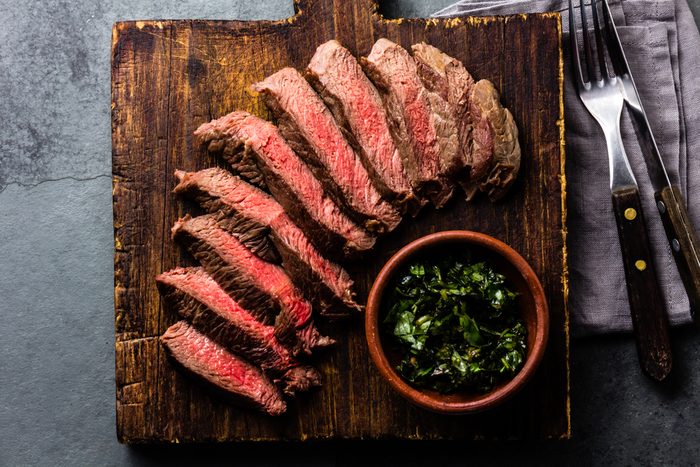 Medium rare sliced beef served on wooden board. Sliced medium rare roast beef on slate gray background
