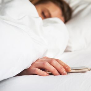 woman sleeping in bed being woken by mobile phone