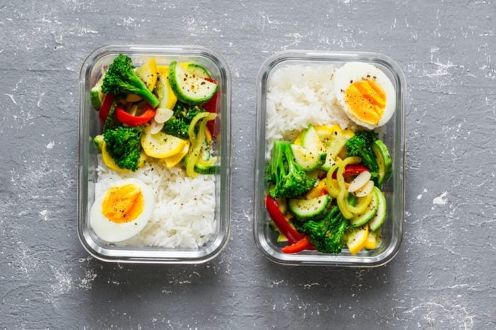Vegetarian lunch box - stewed vegetables, rice and boiled egg on a gray background, top view. Health food concept