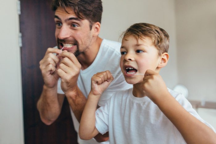 father and son flossing teeth