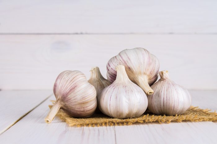 Garlic cloves and garlic bulb on a white wooden table