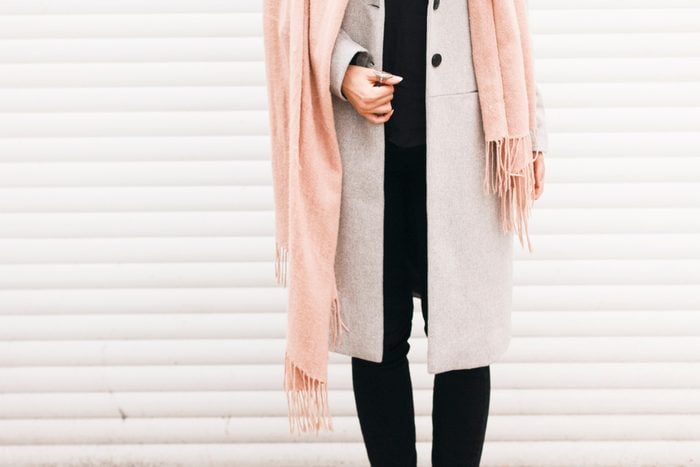 Details of everyday elegant look. Unrecognizable model wearing casual outfit. Gray coat and pink scarf in trendy minimalistic style. Street fashion for spring or fall season.