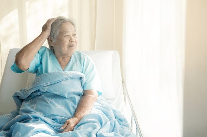 Elderly patient alone in bed. Alone and stress, missing her grand children. Looking at window. Very senior, old chinese woman.