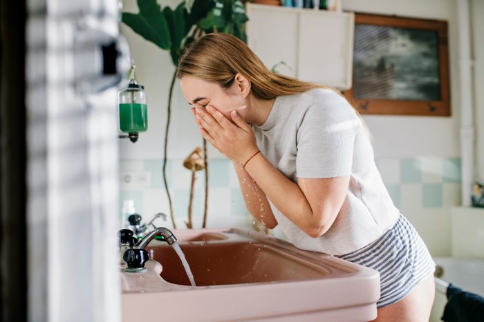 woman washing face in bathroom