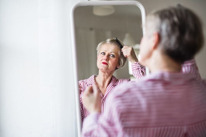 woman looking in mirror and brushing hair