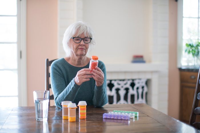 senior woman reading the label of a medication bottle