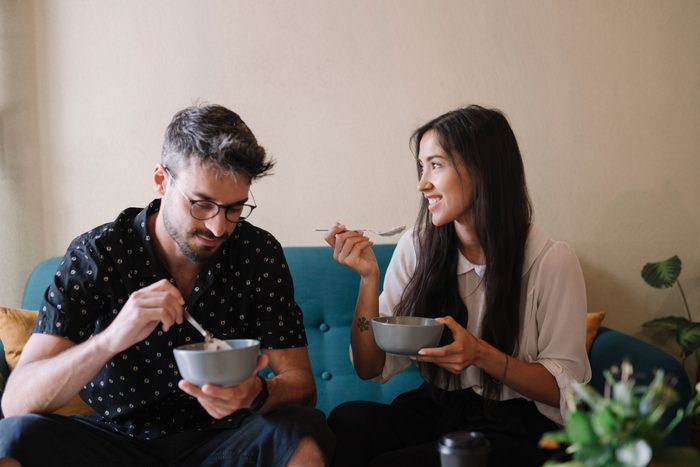 couple sitting on couch eating breakfast