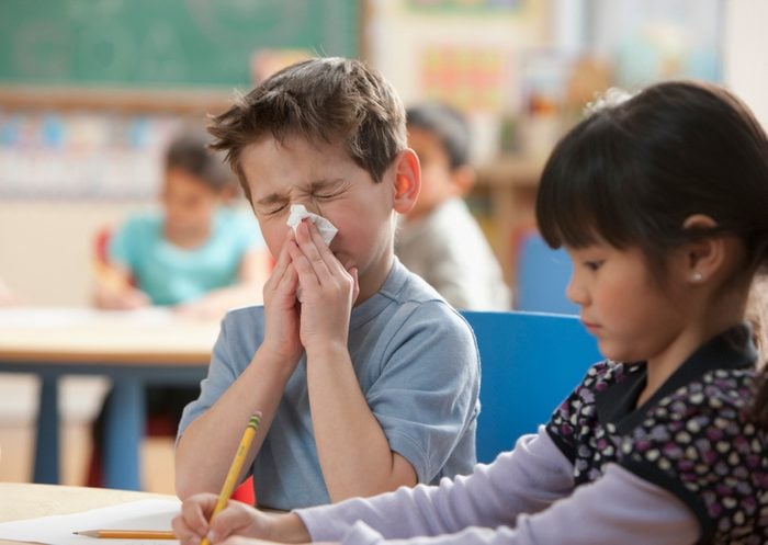 young boy blowing his nose at school