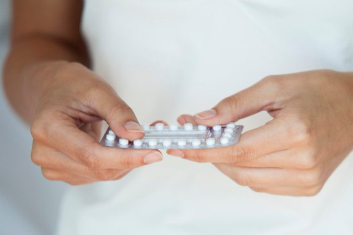 woman holding pack of birth control pills cropped close up shot