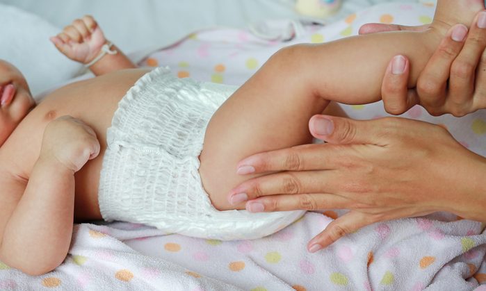 Close up of mother hands put on a baby diaper to her newborn.