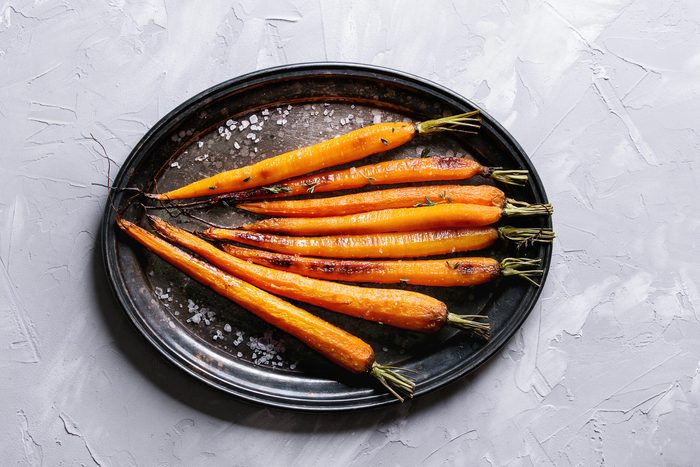 cooked, whole carrots on a black plate