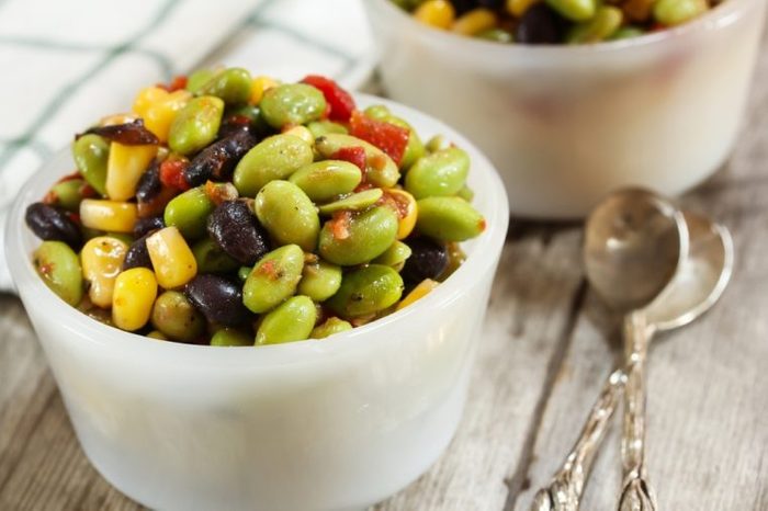 Edamame salad in small white bowl with spoons