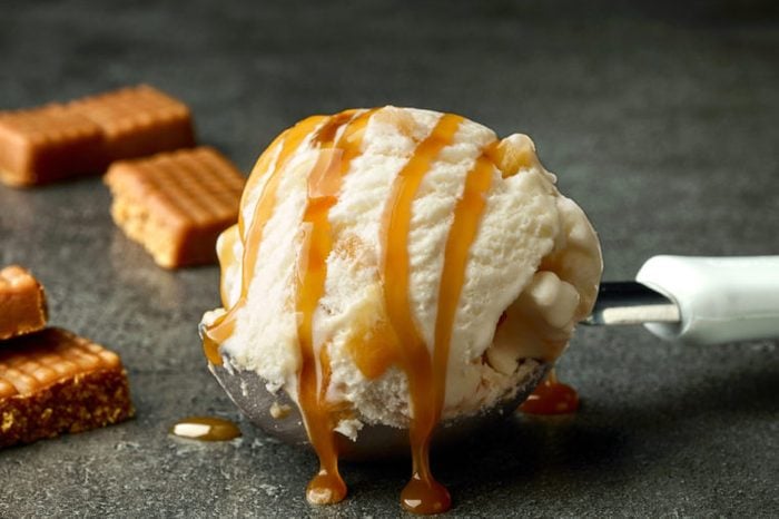 Scoop of ice cream with caramel sauce on dark gray table