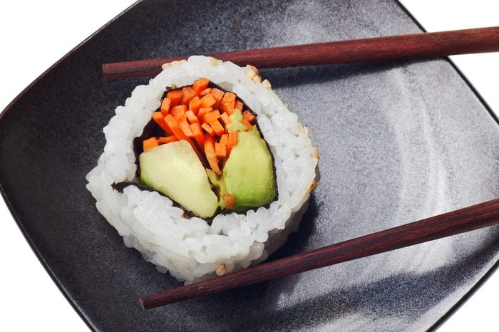 Vegetarian sushi California roll with rice and seaweed with chopsticks on black plate