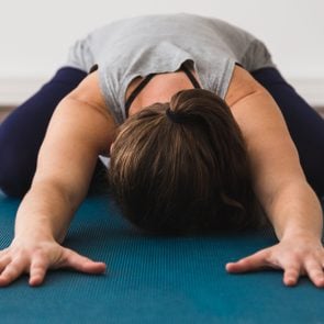 Young attractive woman on yoga mat doing child's pose